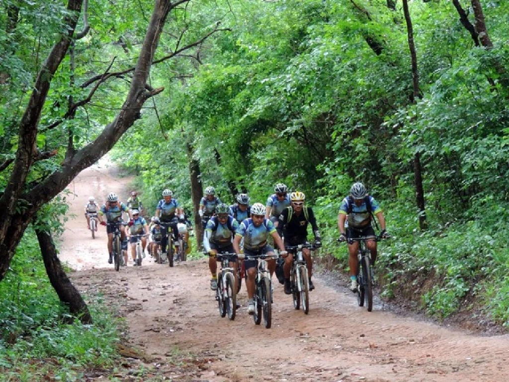 Ciclistas pedalando ao longo de trilha arborizada de terra batida no Cariri